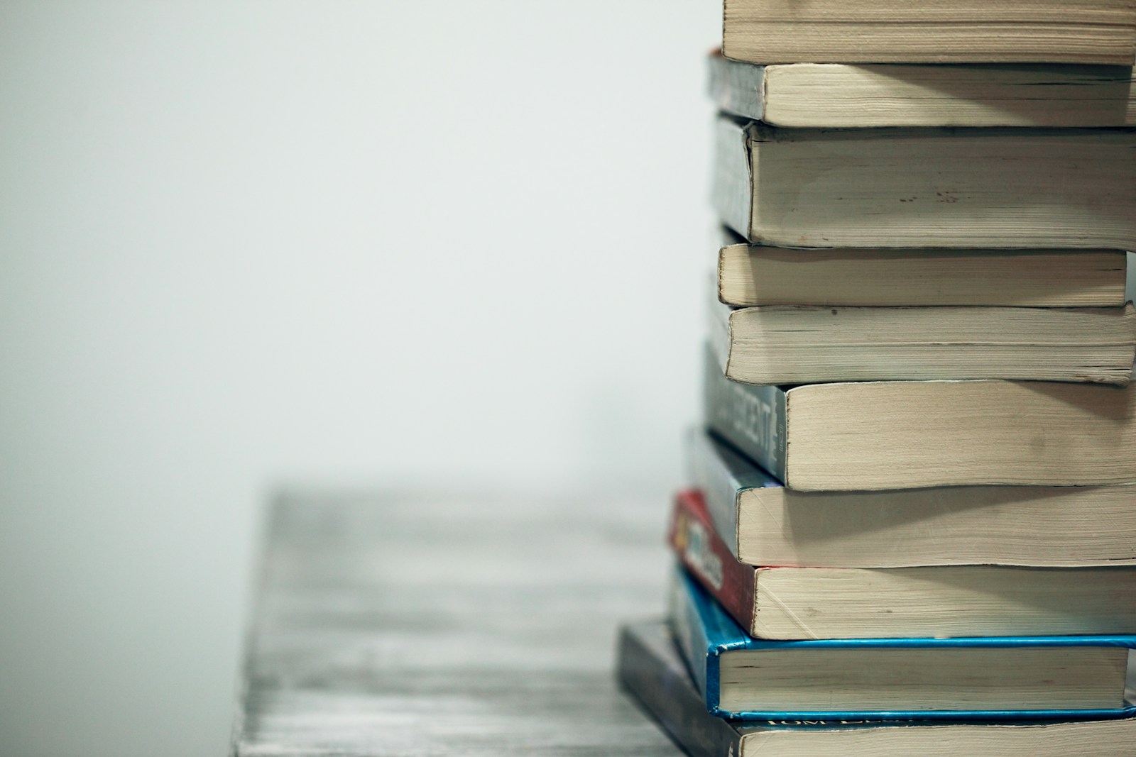 A stack of well-read books on a wooden table